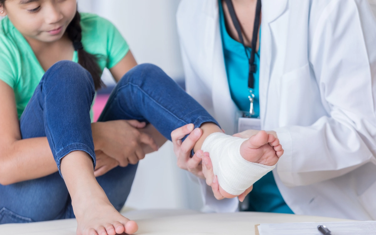 Médico examinando el tobillo lesionado de una niña