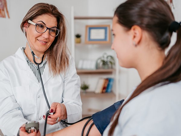 Una mujer joven sentada recibiendo atención de una doctora.