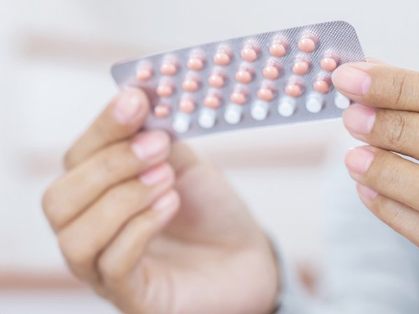 Una mujer sosteniendo un paquete de pastillas anticonceptivas.
