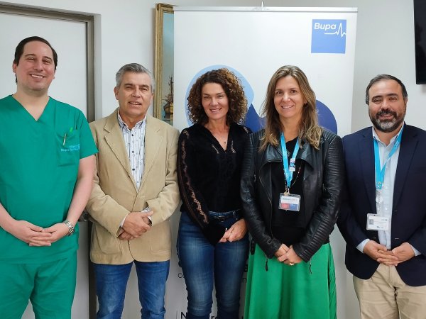 Grupo de profesionales posando frente a un banner de la Clínica Bupa Reñaca.