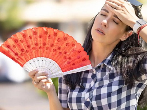 Mujer con un abanico rojo en la mano, intentando refrescarse del calor.
