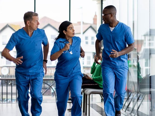 Tres profesionales de la salud apresurándose en un pasillo de un centro médico.