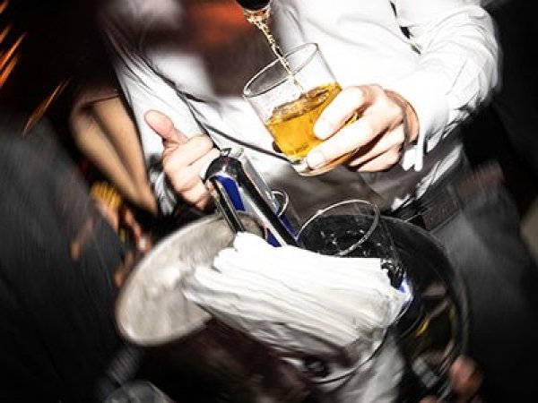 Persona desenfocada sosteniendo una botella de alcohol en una fiesta.